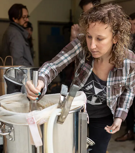 nainen sekoittaen vedenkeitintä homebrew-prosessin aikana' title='Voivatko naiset pelastaa kotipanimon?