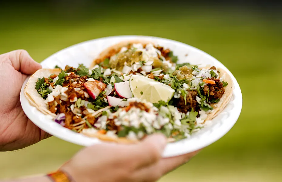 Teller mit Tacos in Händen gehalten' title='Tacos