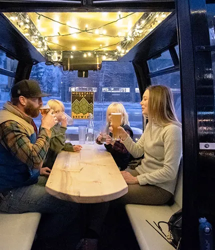 család élvezi a sört a szabadtéri jégkunyhóban egy sörfőzdében' title='Egy sör