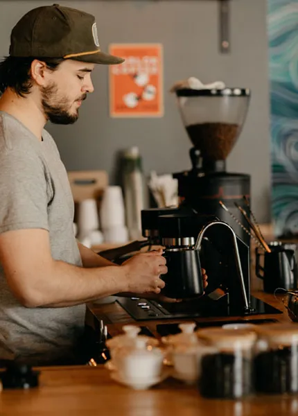 man förbereder kaffe i bryggeri' title='Rise and Shine: Brewers Add Coffee