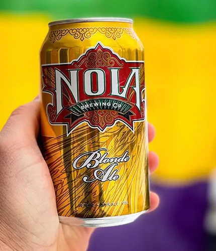 main tenant une canette de bière blonde nola' title='La bière dans une ville de cocktails : comment les brasseries artisanales ont enrichi NOLA